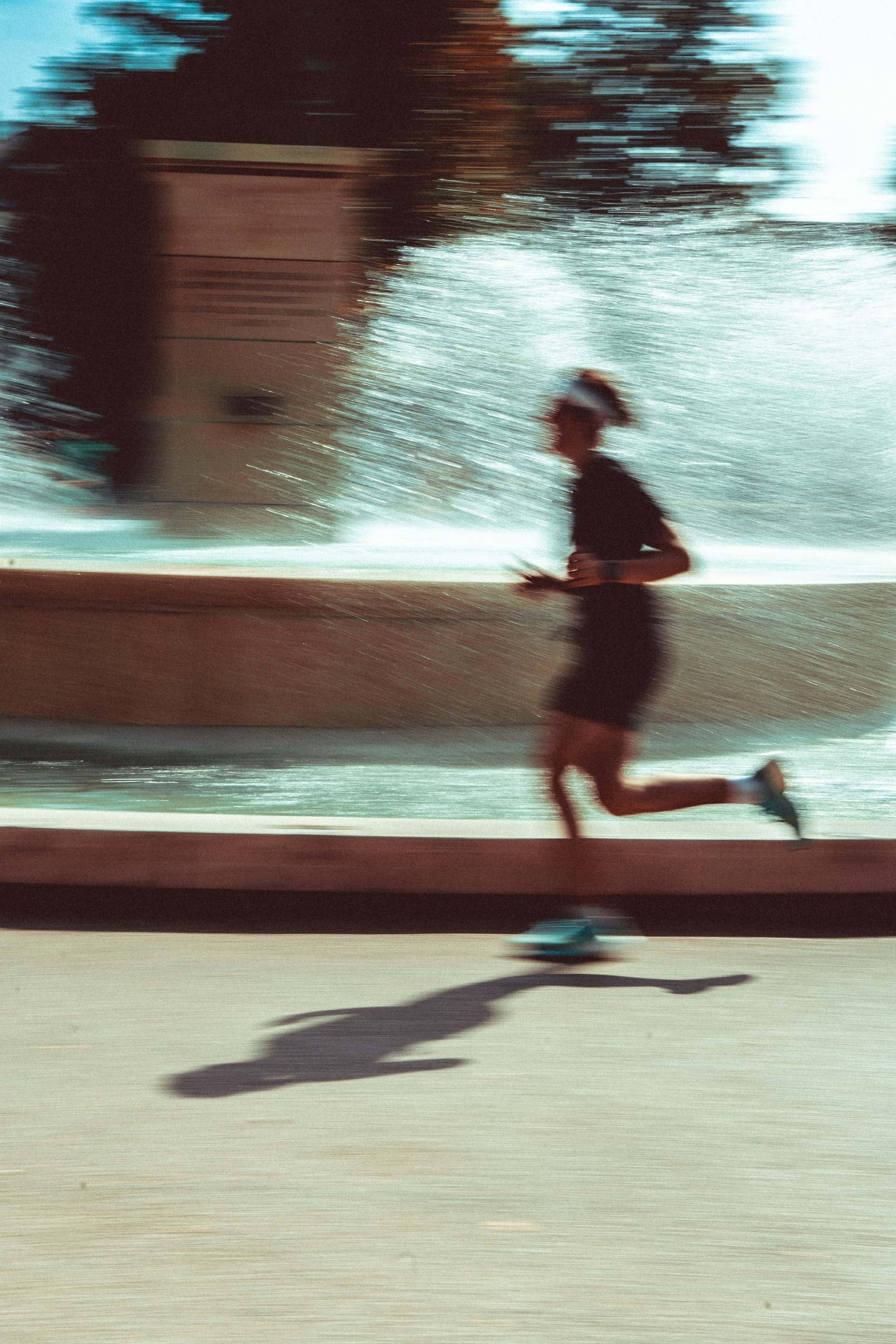 A runner mid-stride, motion-blurred, passing a sunlit fountain