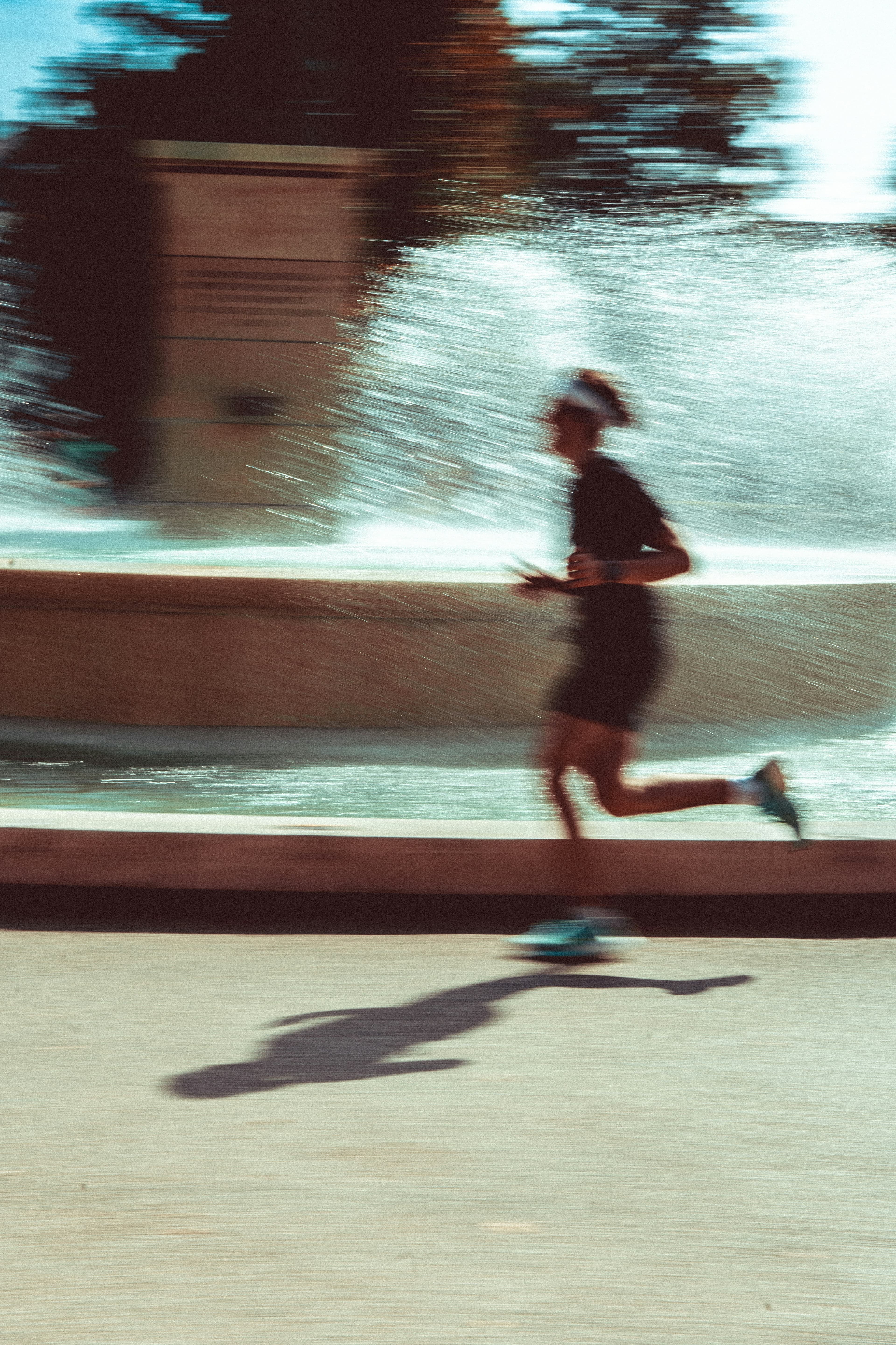 A runner mid-stride, motion-blurred, passing a sunlit fountain